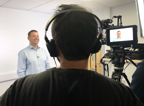 SubTera fundraising film man with a video camera filming a person stand against a white background